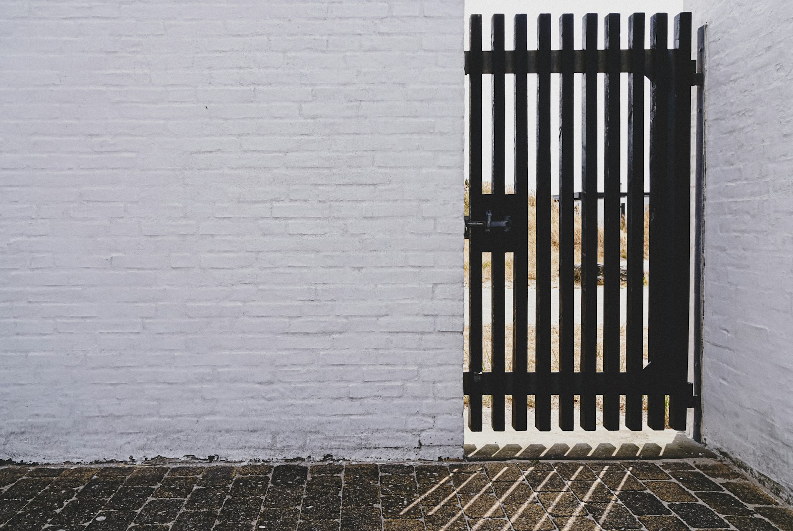 Portão pedonal metálico preto em muro branco